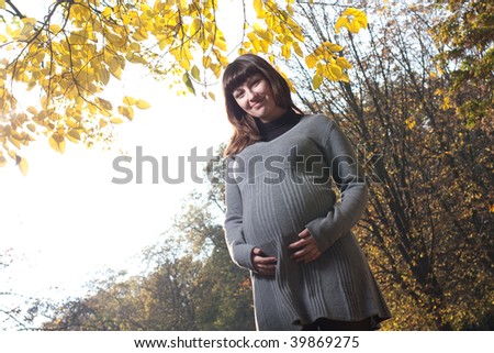 Pleasured pregnant woman in autumn park