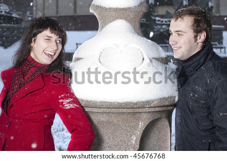 Young beautiful couple playing in winter park. Girl wink to her boyfriend