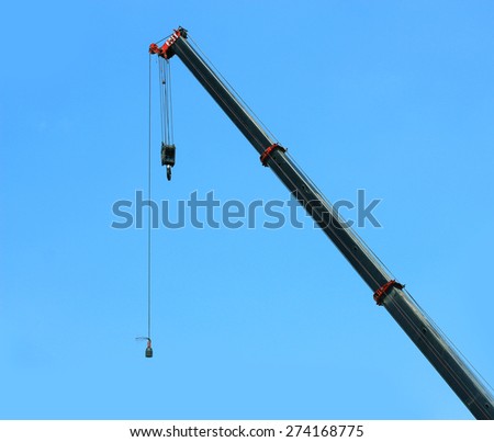 automobile crane with risen telescopic boom outdoors over blue sky