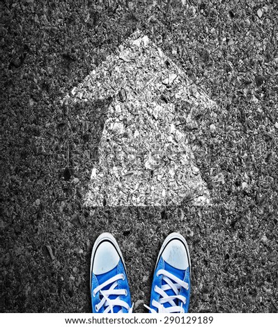 Male sneakers on the asphalt road with direction arrow