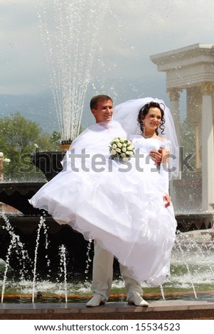 The groom and the bride near a fountain