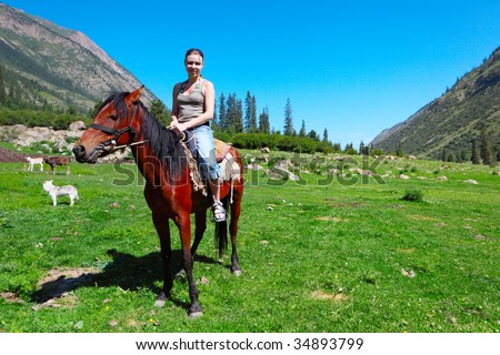 The girl astride a horse in mountains