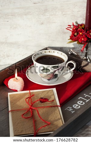 Valentine's day gift card and cup of coffee on wooden tray, celebration still-life.