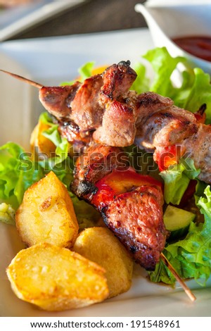 Fresh hot, barbecue, grilled meet with fried potato and vegetables. Russian shashlik.