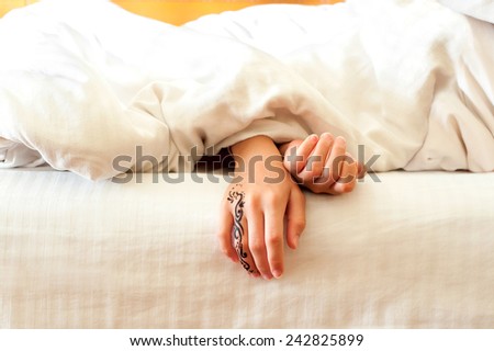 Little sleeping child hands with tattoo on white bed linen. Indoors closeup.