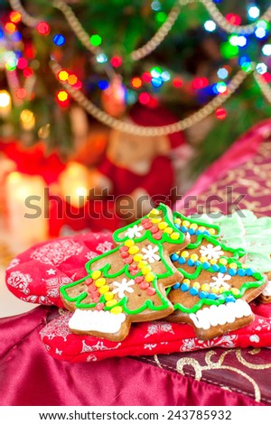 Homemade christmas tree shape gingerbread cookies on oven mitten. Illuminated festive background