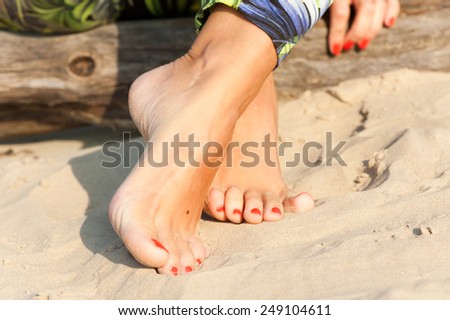 Tidy tanned sexual soft woman feet on the beach sand. Summertime outdoors close-up.