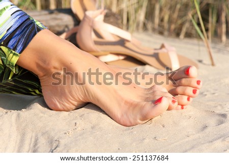 Tidy tanned sexual soft woman feet on the beach sand. Summertime outdoors close-up.