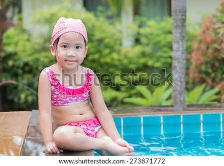 Little cute Asian girl on bikini suit in swimming pool.