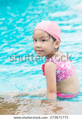 Little cute Asian girl on bikini suit in swimming pool.