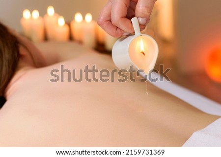 Relaxing massage and aromatherapy with candle and wax. Back of unrecognizable woman, lying on bed in a massage parlor. Stok fotoğraf © 