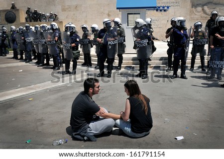 ATHENS, GREECE - MAY 20: A young couple of anti-cuts protesters, sits peacefully opposite the riot police officers in front of Greek Parliament ,in Athens, May 20, 2010.