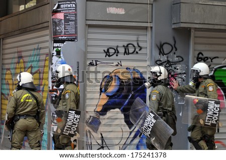 ATHENS, GREECE - DECEMBER 07. Riot police officers wearing a gas mask in front of graffiti of a gas mask, during clashes in Athens, December 07, 2008.