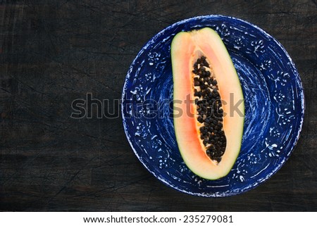 Papaya in a blue plate on the dark wooden table horizontal
