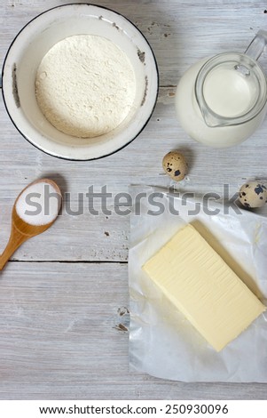 Ingredients for the pancakes on the white wooden table around the parchment roll