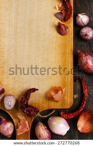 Wooden board with onions, garlic and pepper background vertical