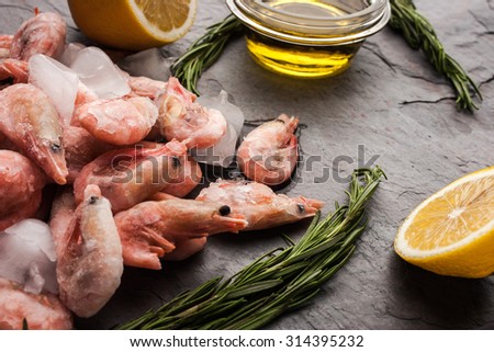 Frozen shrimps  with rosemary, lemon and olive oil on the black stone table
