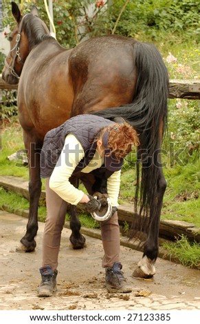 A woman cleans a  hoof of horse.