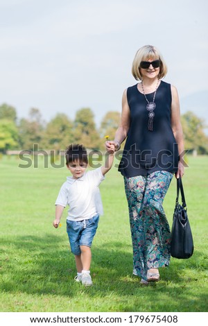 Grandmother and his grandson are walking in the park.