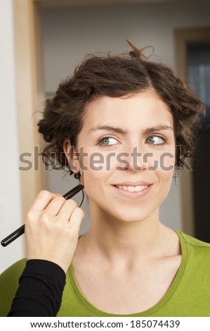 Portrait of beautiful young woman getting her make up done