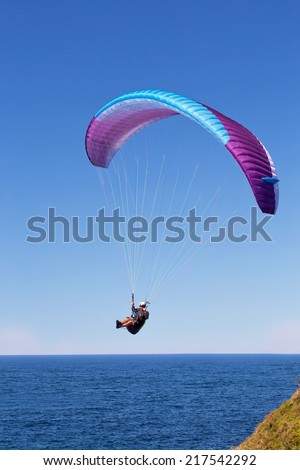 WARRIEWOOD,AUSTRALIA - SEPTEMBER 14, 2014: A man enjoys some time in the air, paragliding along the cliff tops above the beach in the spring sunshine.