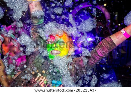 SYDNEY,AUSTRALIA - JUNE 6,2015: A woman in the Color Run Night 5K fun run. Runners encounter bubble blowers, coloured powder and UV light, joining a dance party at the finish.