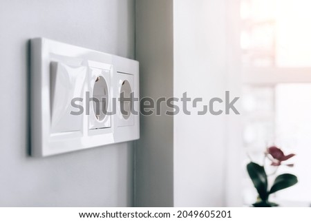 White european electrical socket outlets and switch on gray wall in light modern kitchen by the window. Selective focus Сток-фото © 