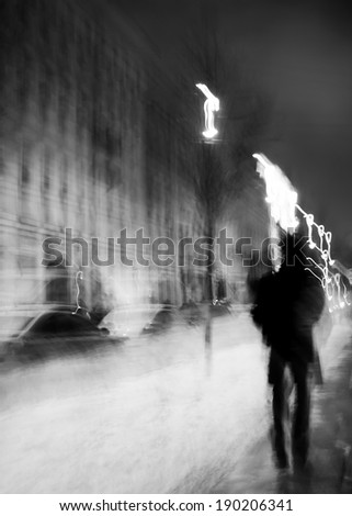 Art photo.Silhouette of a man walking at night on the wet asphalt.