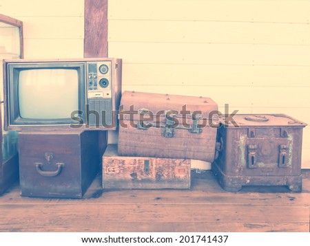 retro tv and boxes on wooden floor with vintage filter effect