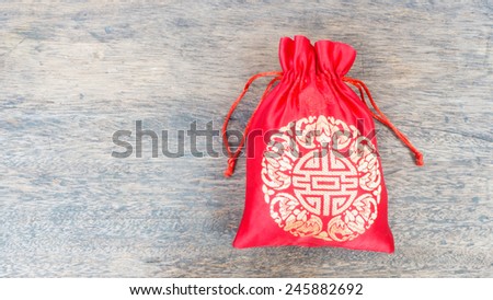 Red silky money bag on wood desk, Lucky Pouch Chinese tradition.