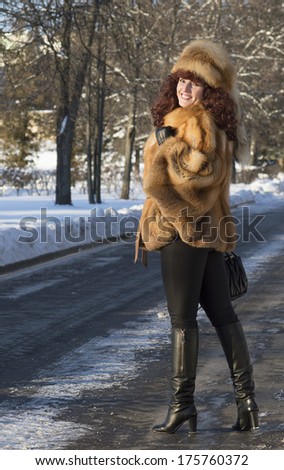 The attractive woman in a fox fur coat looks back and smiles.