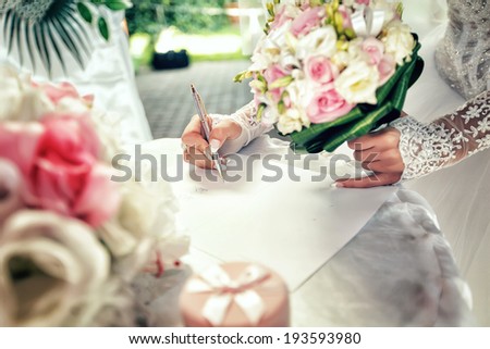Bride signs up document on civil wedding ceremony.