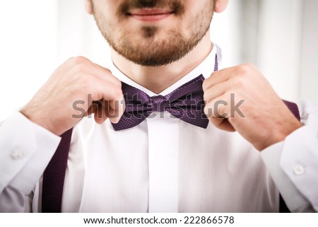 Man puts on violet bow tie. Close up. Shallow depth of field. Focused on bow tie.
