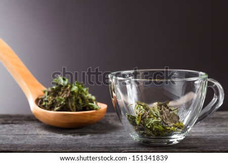 Cup of green mint tea and spoon with dry mint
