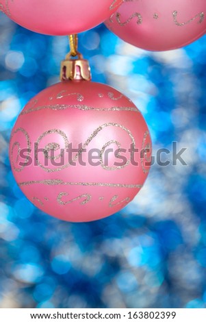 Three pink New Year balls against blue shine background. Space for text