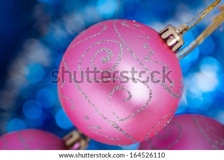 Three pink New Year balls against blue shine background. Space for text