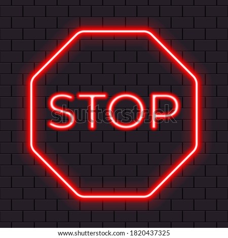 Bright red neon stop sign isolated on a dark brick wall.