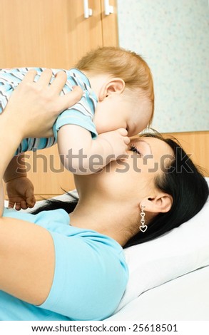 happy family, young brunette mother kissing her ten months old baby