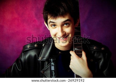 happy handsome young man holding his guitar and smiling