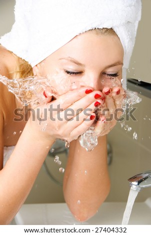 beautiful young woman washing her face in the bathroom