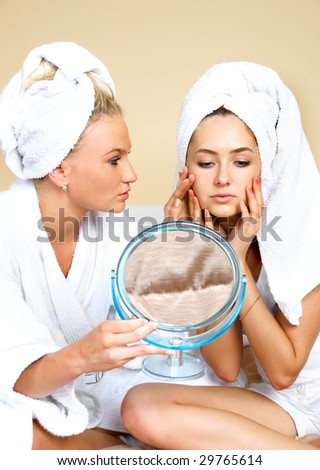 two young women  looking into the mirror, one of them has skin problems