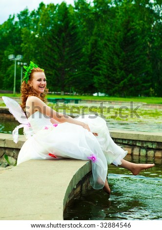 KRASNOYARSK, RUSSIA - JUNE 21: happy bride dressed as a fairy sitting near the fountain at Parade of Brides June 21, 2009 in Krasnoyarsk. The annual summer event takes place in many Russian cities.