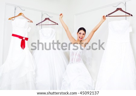 pretty young excited woman is choosing a wedding dress in the shop