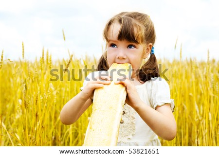 happy cute little girl in the wheat field eating a long loaf