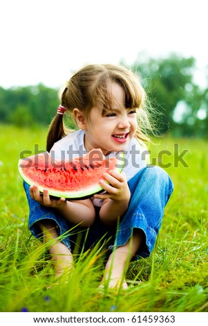 cute little girl eating  water-melon on the grass in summertime