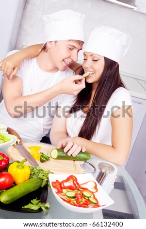 two happy young cooks making salad in the kitchen