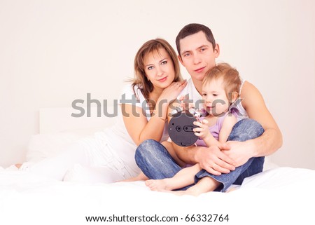 happy family, mother ,father and their baby on the bed at home (focus on the woman and a man)