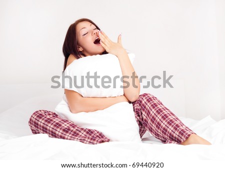 beautiful young woman sitting on the bed and yawning
