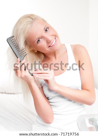 beautiful young blond woman brushing her hair and smiling