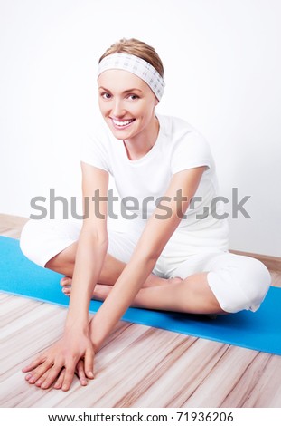 beautiful young blond woman stretching the muscles of her back and legs on the mat at home